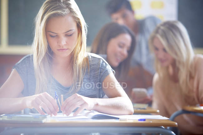 Female student in classroom using compasses — Stock Photo