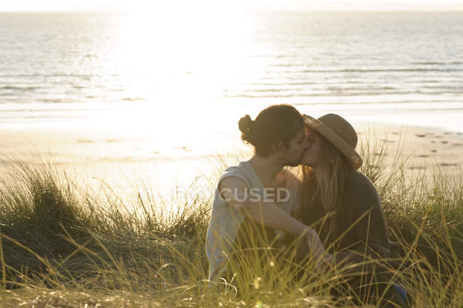 Jeune couple s'embrassant sur les dunes de la plage devant l'océan Atlantique — Photo de stock