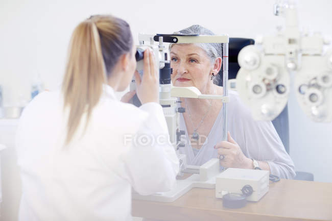 Eye doctor examining senior woman's vision — Stock Photo