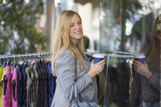 Souriant jeune femme faisant du shopping avec du café à emporter — Photo de stock