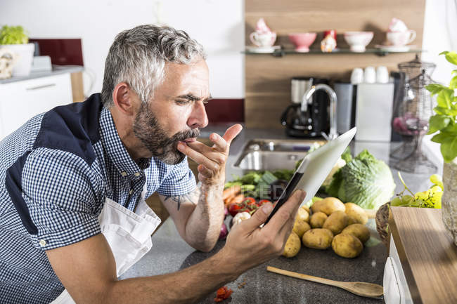 Austria, Hombre en la cocina sosteniendo tableta digital, en busca de receta - foto de stock