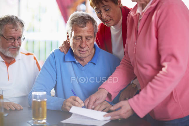 Uomo anziano con gli amici firma documento — Foto stock