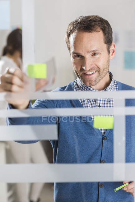 Businessman with adhesive notes at glass pane — Stock Photo