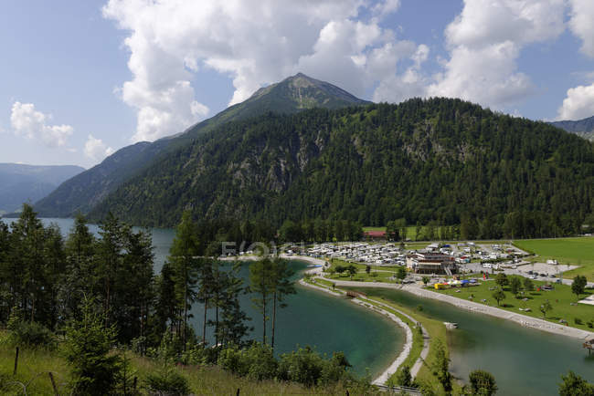 Austria, Tirol, Achensee en Scholastika con Seekarspitze y vista de la colina con árboles sobre el agua - foto de stock