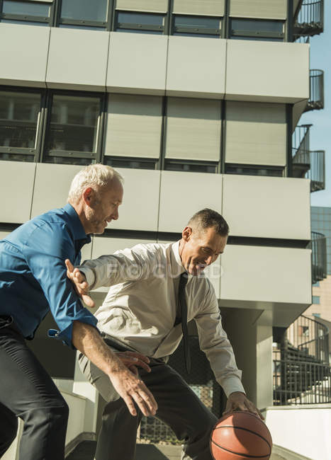 Dois homens de negócios jogando basquete fora do prédio de escritórios — Fotografia de Stock