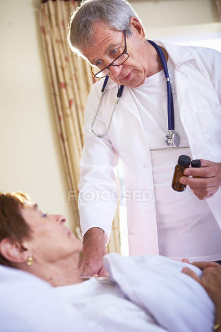 Medico parlando con anziano donna sdraiato in ospedale letto — Foto stock