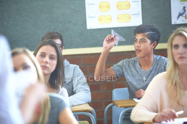 Student in classroom throwing paper plane during lesson — Stock Photo