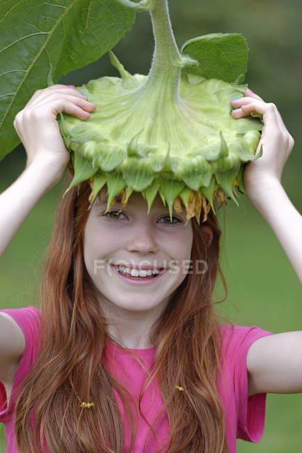 Ritratto di ragazza sorridente che tiene il fiore di girasole sulla testa — Foto stock