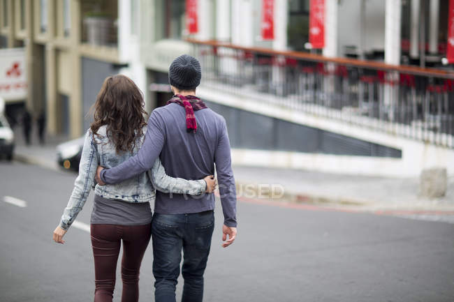 Молода пара з обіймами, що йдуть по вулиці — стокове фото