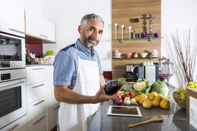 Austria, Hombre en la cocina con tableta digital preparando alimentos - foto de stock