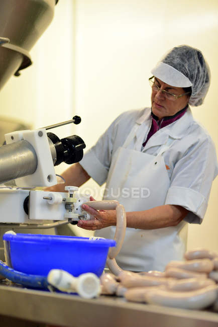 Woman working at sausage production in a butchery — Stock Photo