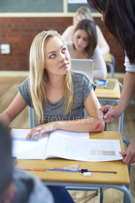 Teacher explaining something to student in classroom — Stock Photo