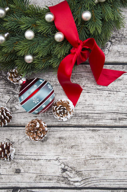 Ghirlanda d'Avvento con fiocco rosso, bagattelle natalizie e coni di abete su legno — Foto stock