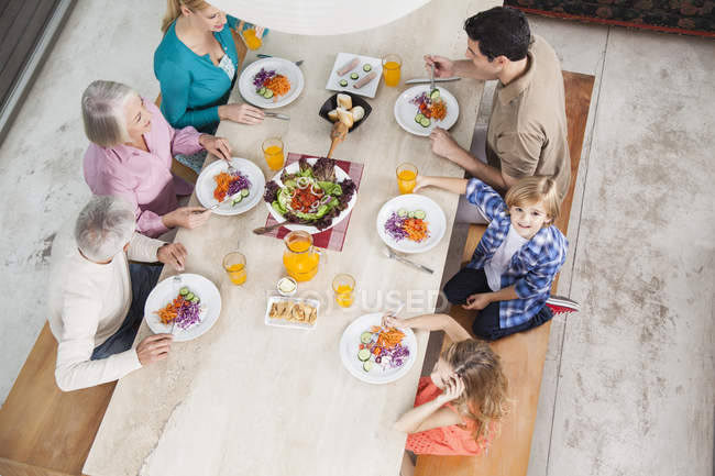 Extended family with salad and juice at dining table — Stock Photo