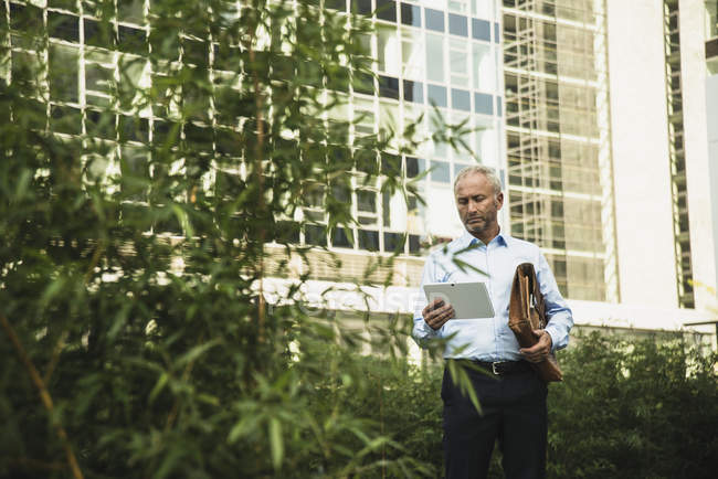 Geschäftsmann hält digitales Tablet vor Bürogebäude — Stockfoto