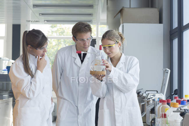 Tres químicos trabajando en un laboratorio químico - foto de stock