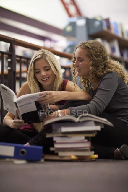 Duas estudantes do sexo feminino aprendendo em uma biblioteca — Fotografia de Stock