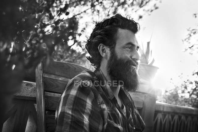 Hombre sonriente con barba llena en el porche - foto de stock