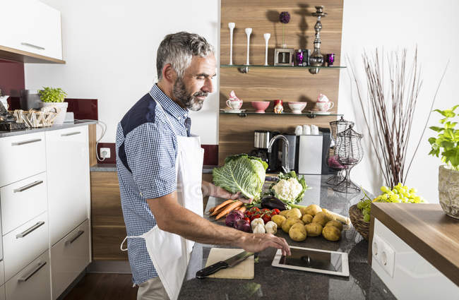 Österreich, Mann in Küche mit digitalem Tablet bereitet Essen zu — Stockfoto