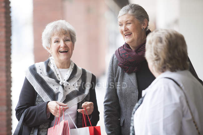 Tres mujeres mayores riendo en viaje de compras - foto de stock