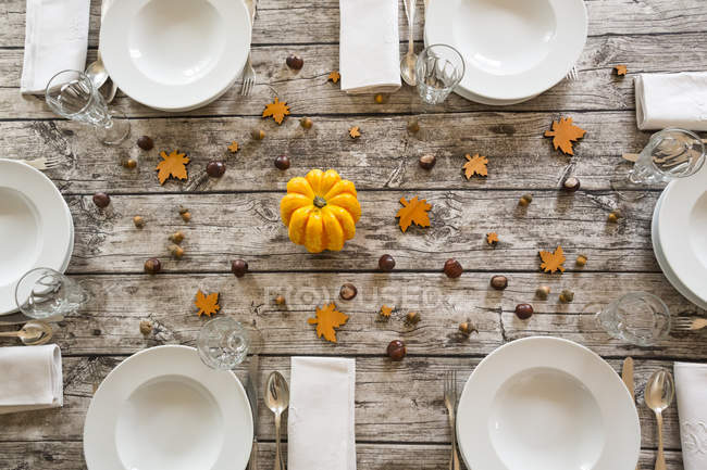 Autumnal laid table with yellow pumpkin, chestnuts and acorns — Stock Photo