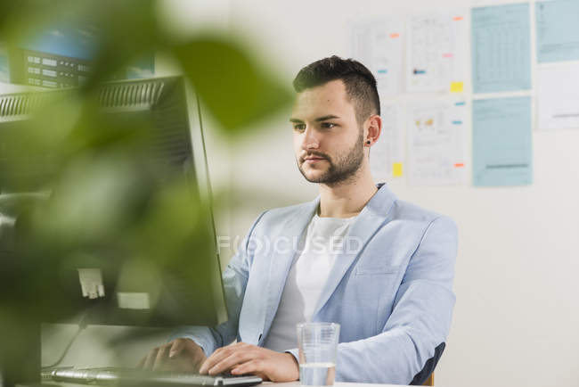 Joven hombre de negocios en la oficina trabajando en la computadora - foto de stock