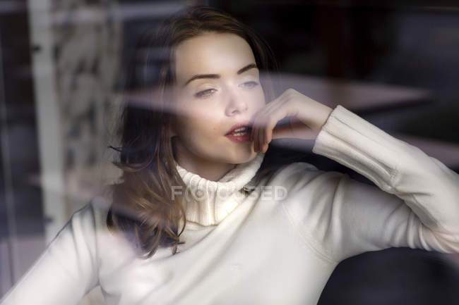 Портрет стомлюючої молодої жінки, яка дивиться через віконну панель кафе — стокове фото