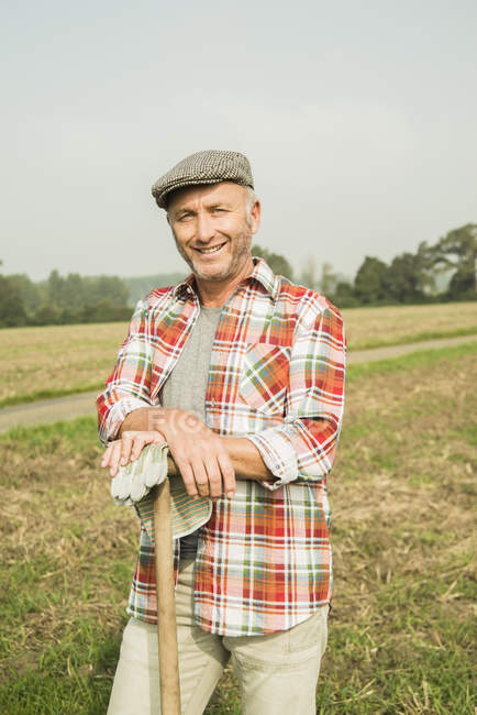 Retrato del granjero sonriente parado frente a un campo - foto de stock