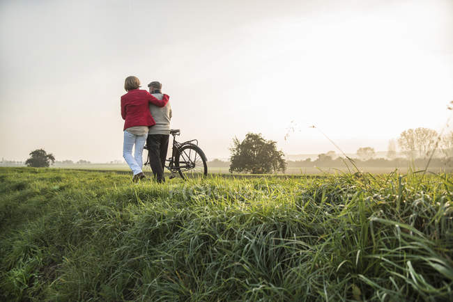 Senior man and daughter in rural landscape with bicycle — Stock Photo