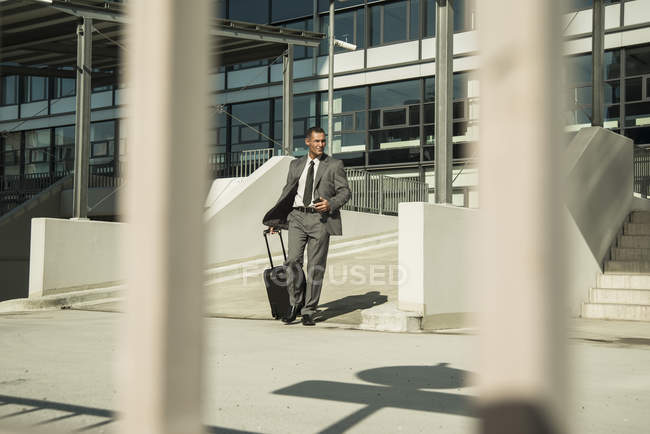 Businessman with suitcase outside office building — Stock Photo