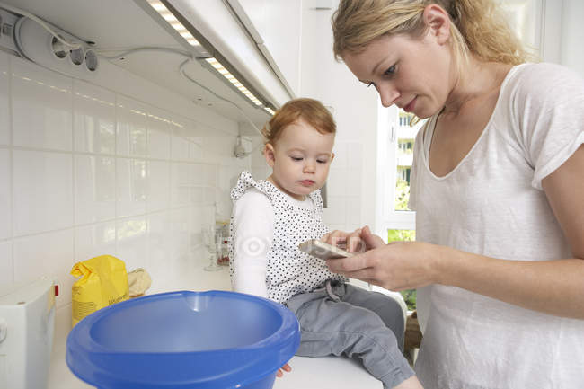 Mother and little daughter baking cake together — Stock Photo