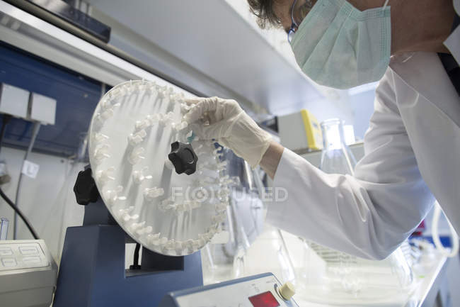 Technicienne qui soumet un échantillon à un rotateur au laboratoire de biochimie — Photo de stock