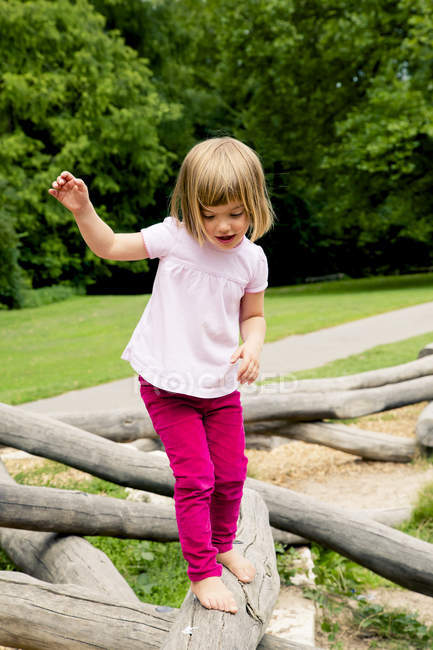 Kleines Mädchen balanciert auf Spielplatz auf Baumstamm — Stockfoto