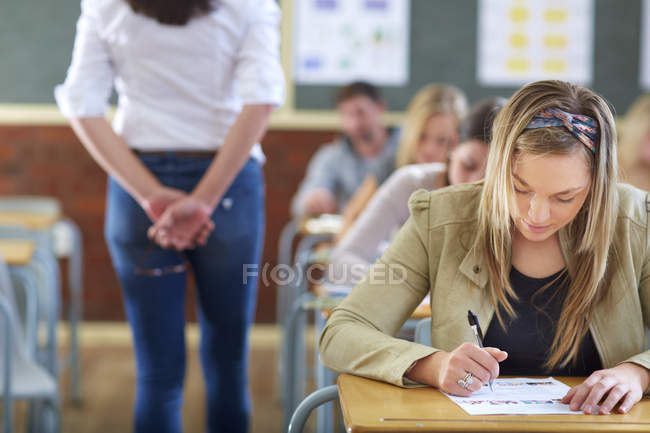 Cropped portrait of students and teacher in classroom during an exam — Stock Photo