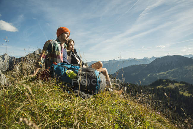 Austria, Tirol, Tannheimer Tal, pareja joven descansando en las montañas - foto de stock