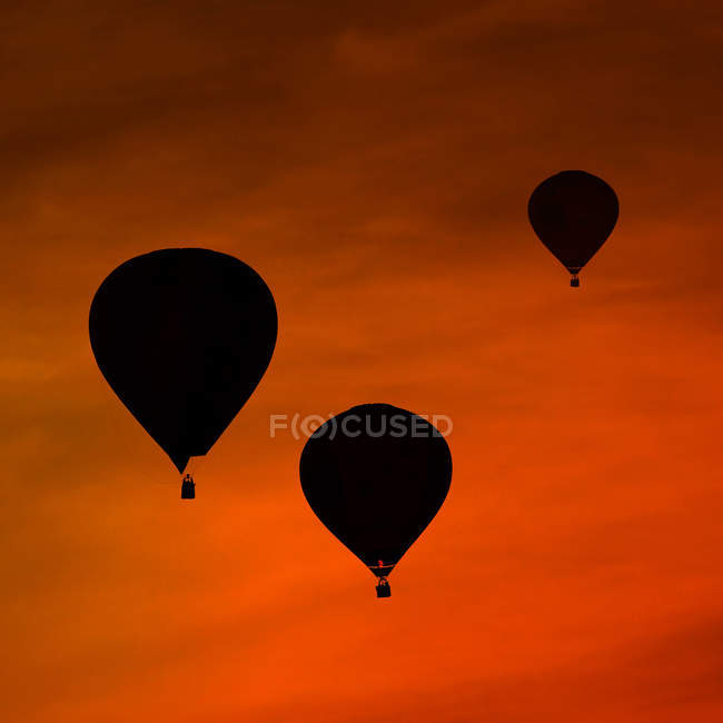 Silhuetas de três balões de ar na frente do céu vermelho da noite — Fotografia de Stock