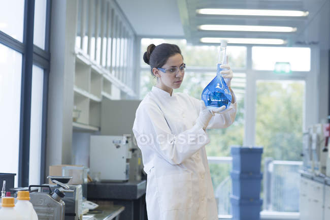 Жіночий вченого, стоячи з лампа скла в хімічної лабораторії — стокове фото