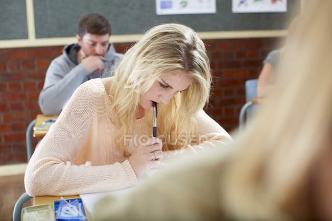 Female student in classroom writing an exam — Stock Photo