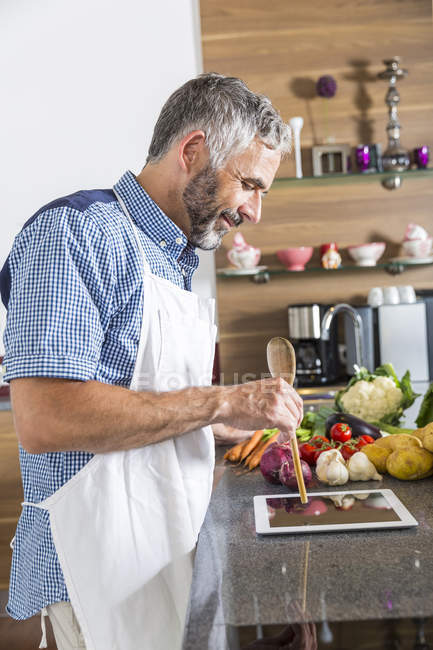 Austria, Hombre en la cocina con tableta digital preparando alimentos - foto de stock