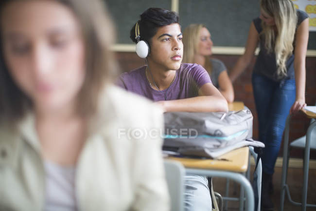 Student wearing headphones in classroom and looking aside — Stock Photo