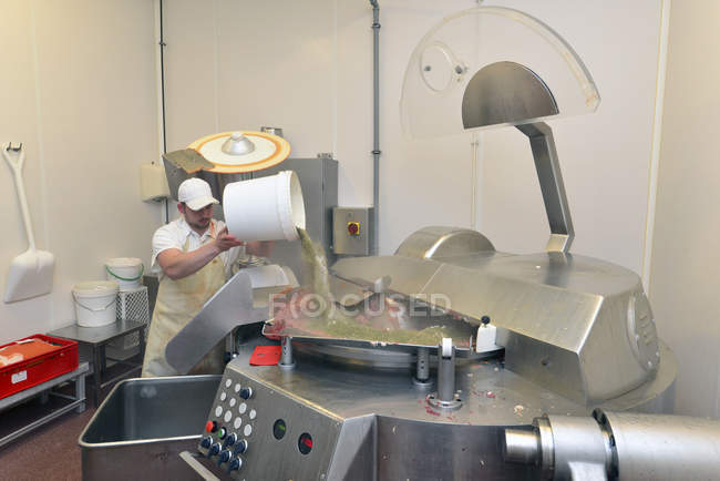 Man pouring spices into silent cutter in a butchery — Stock Photo