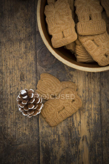 Cuenco de galletas de almendras y cono de abeto sobre madera - foto de stock