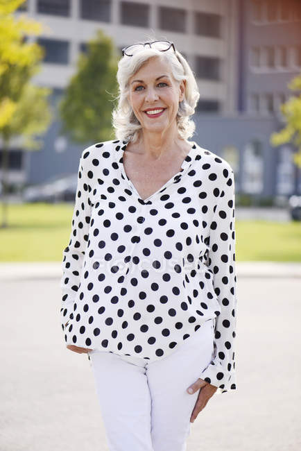 Retrato de mulher sênior sorridente vestindo blusa branca com pontos pretos — Fotografia de Stock
