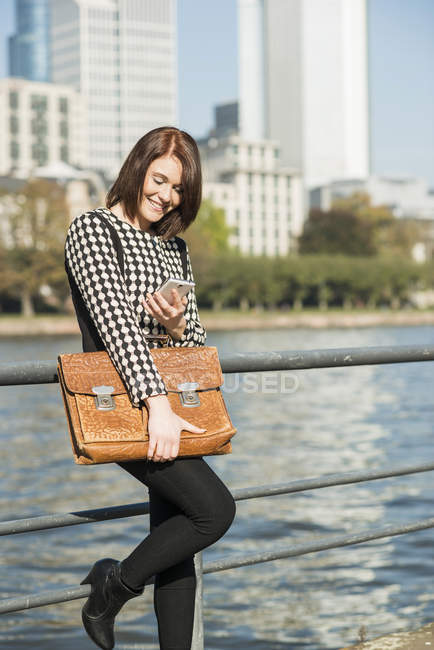 Германия, Франкфурт, молодая деловая женщина у реки с сотовым телефоном — стоковое фото