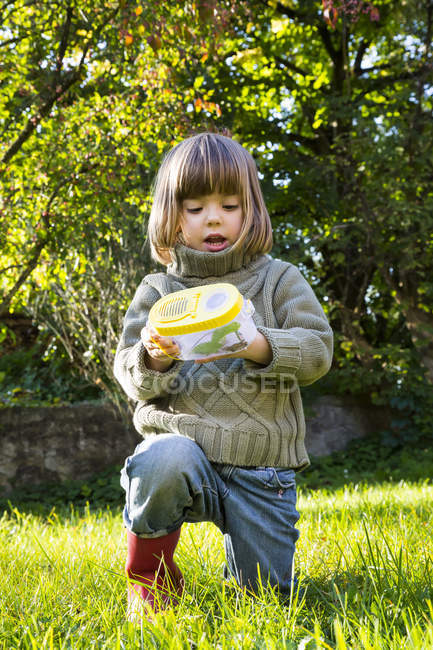 Little girl with insect can on grassy lawn — Stock Photo