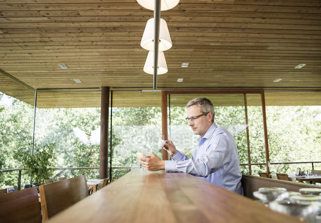 Homme d'affaires dans un café utilisant un téléphone portable — Photo de stock