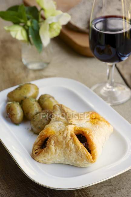 Puff pastry parcels with a chestnut mushroom filling, potatoes and a glass of wine — Stock Photo
