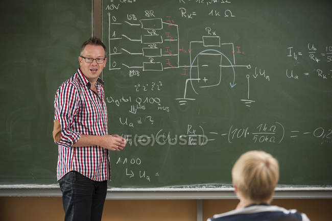 Vocational school student in classroom with teacher at blackboard — Stock Photo