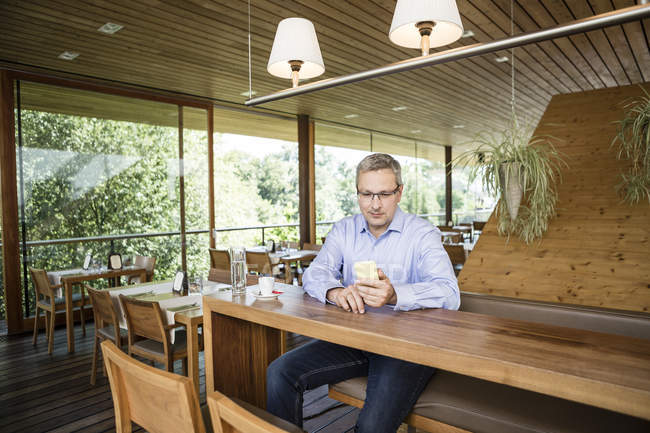 Homme d'affaires dans un café utilisant un téléphone portable — Photo de stock