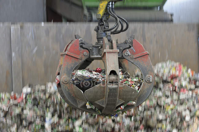 Clamshell grabbing aluminium cans in a scrap metal recycling plant — Stock Photo